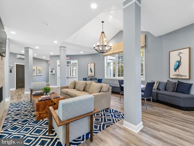 living room with lofted ceiling, a tiled fireplace, light wood-type flooring, a notable chandelier, and decorative columns