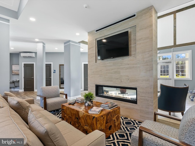 living room with a fireplace, hardwood / wood-style flooring, and a wall unit AC