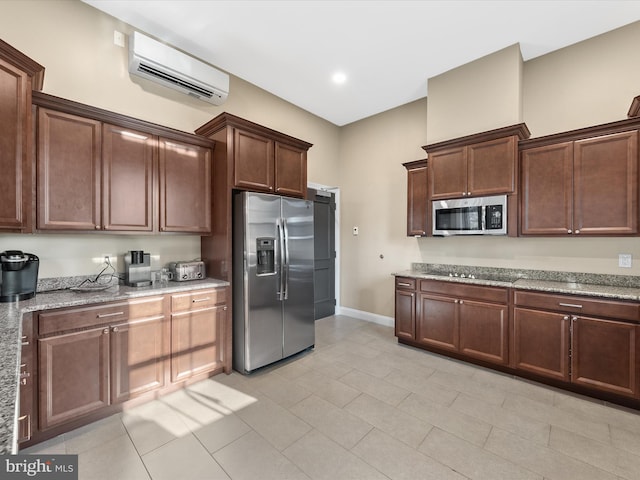 kitchen with an AC wall unit, light stone countertops, appliances with stainless steel finishes, dark brown cabinets, and light tile patterned flooring