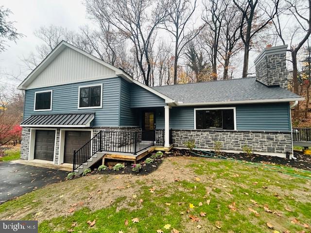 tri-level home featuring a front lawn, a porch, and a garage