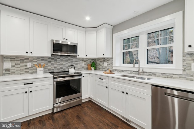 kitchen featuring backsplash, white cabinets, sink, appliances with stainless steel finishes, and dark hardwood / wood-style flooring