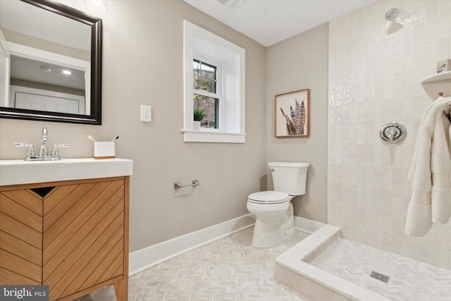 bathroom featuring vanity, toilet, and tiled shower