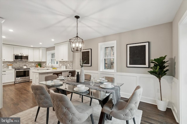 dining area with dark wood-type flooring and an inviting chandelier