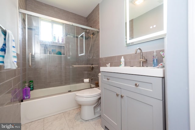 4504 Harbor Beach Blvd, Brigantine, NJ 08203 - bathroom featuring tile walls, toilet, vanity, shower / bath combination with glass door, and marble look tiles