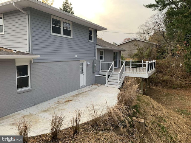 back house at dusk featuring a patio area and a wooden deck