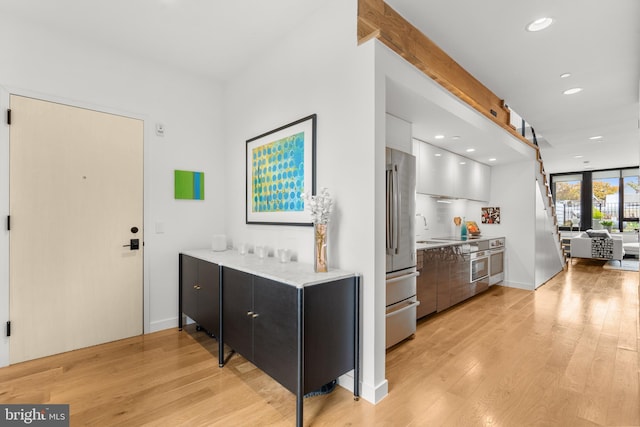 interior space featuring stainless steel refrigerator, white cabinetry, light hardwood / wood-style flooring, and sink