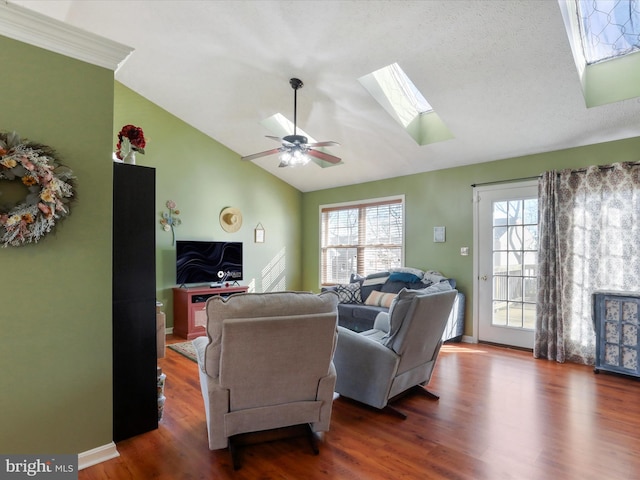 living room featuring dark hardwood / wood-style flooring, ceiling fan, vaulted ceiling with skylight, and a textured ceiling