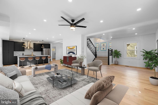 living room featuring light hardwood / wood-style flooring, ceiling fan, and sink