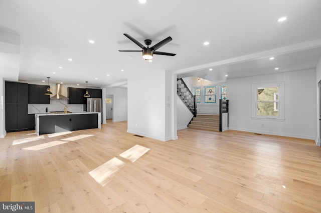 unfurnished living room featuring ceiling fan, light hardwood / wood-style flooring, and sink