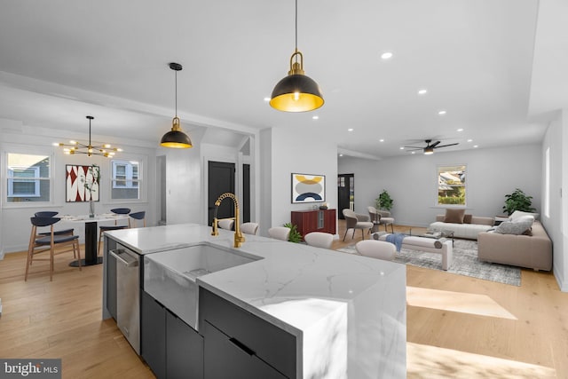 kitchen with light wood-type flooring, decorative light fixtures, a large island, and sink