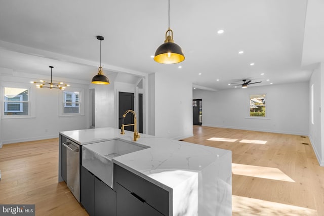 kitchen featuring stainless steel dishwasher, decorative light fixtures, a spacious island, and light wood-type flooring