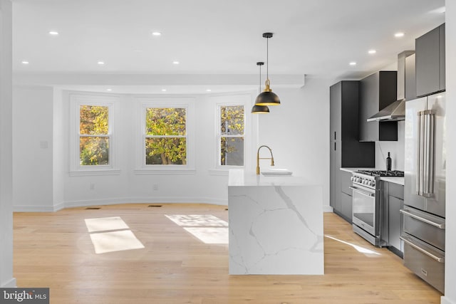 kitchen featuring light stone countertops, pendant lighting, light wood-type flooring, and high quality appliances