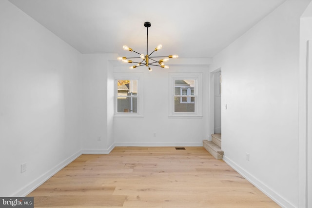 empty room featuring light hardwood / wood-style floors and a notable chandelier