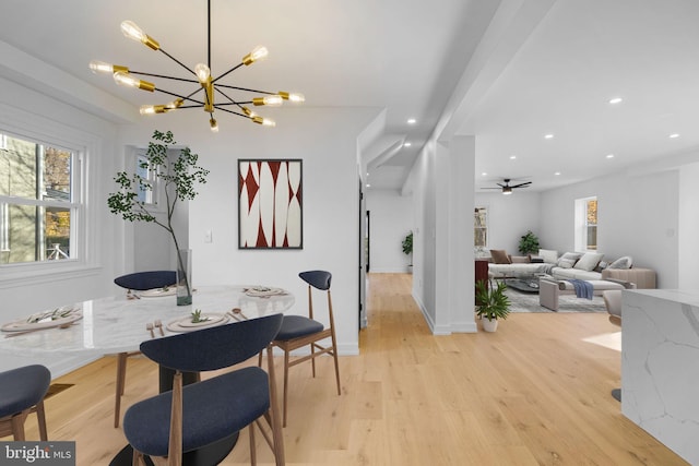 dining area with light hardwood / wood-style floors and ceiling fan with notable chandelier