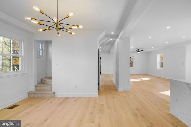 unfurnished living room with light hardwood / wood-style flooring and ceiling fan with notable chandelier