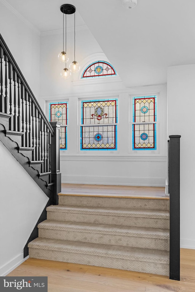 stairs with hardwood / wood-style floors, an inviting chandelier, and ornamental molding