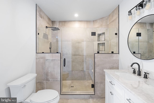 bathroom featuring toilet, vanity, and walk in shower