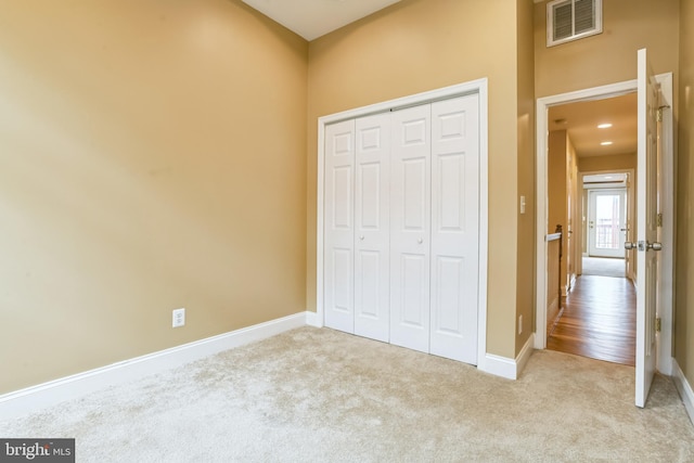 unfurnished bedroom with light carpet and a closet