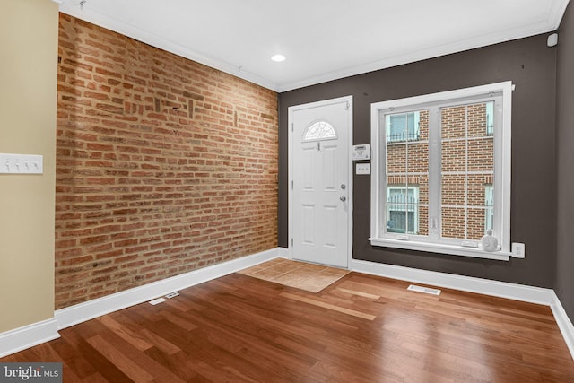 entrance foyer with ornamental molding, brick wall, and hardwood / wood-style flooring