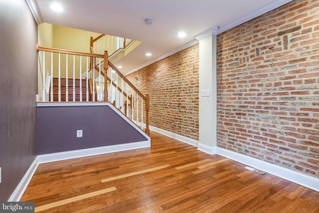 interior space featuring hardwood / wood-style flooring, crown molding, and brick wall