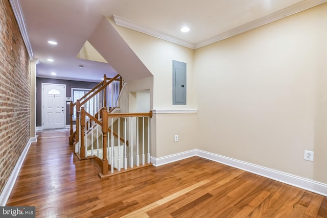 hall featuring brick wall, wood-type flooring, crown molding, and electric panel