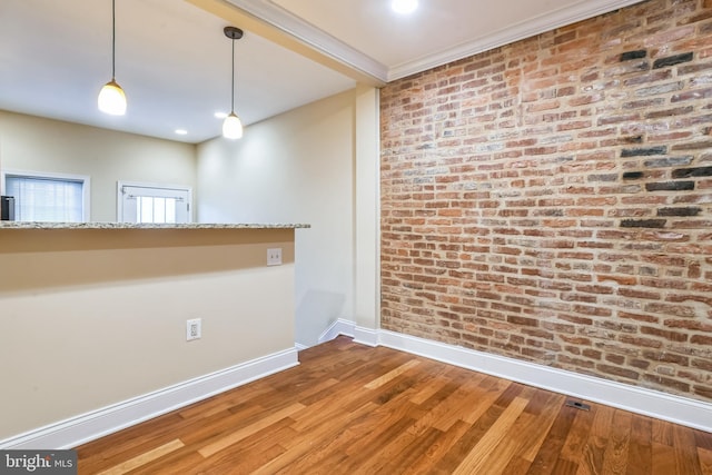 empty room featuring hardwood / wood-style floors and brick wall