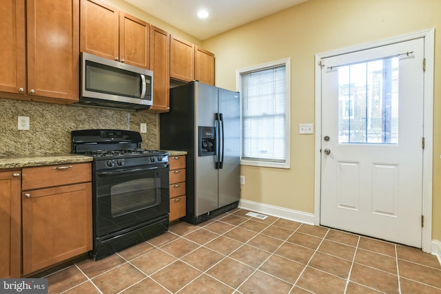 kitchen featuring backsplash, light stone countertops, tile patterned flooring, and stainless steel appliances