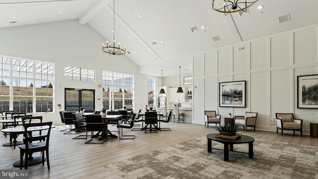 living room featuring wood-type flooring, an inviting chandelier, high vaulted ceiling, and beam ceiling