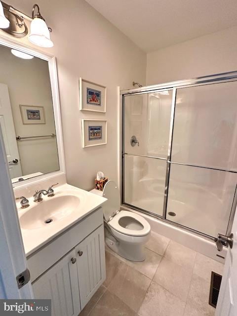 bathroom featuring tile patterned floors, vanity, toilet, and a shower with door