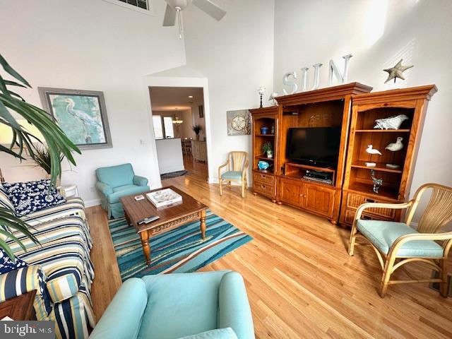 living room featuring a towering ceiling, hardwood / wood-style flooring, and ceiling fan