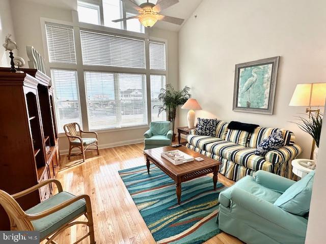 living area featuring ceiling fan, light hardwood / wood-style floors, and high vaulted ceiling