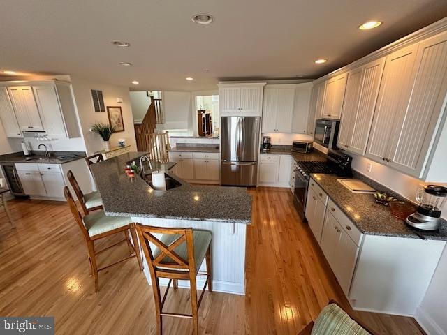 kitchen with light hardwood / wood-style floors, sink, white cabinetry, and stainless steel appliances