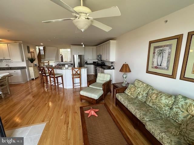 living room with ceiling fan, light hardwood / wood-style floors, and sink