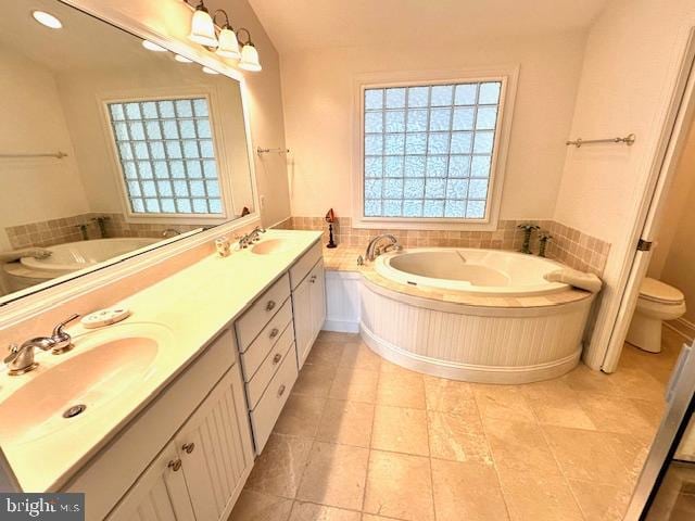 bathroom featuring tile patterned flooring, vanity, toilet, and a bath