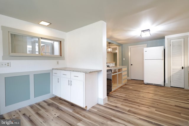 kitchen with white cabinets, light wood-type flooring, white refrigerator, and light stone counters