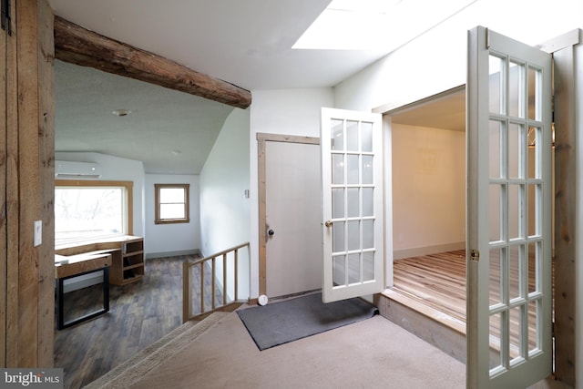 interior space with a wall mounted air conditioner, french doors, dark hardwood / wood-style floors, and vaulted ceiling with skylight