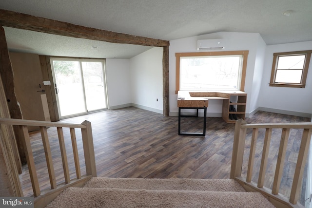 interior space featuring hardwood / wood-style floors, a wall unit AC, a textured ceiling, and a wealth of natural light