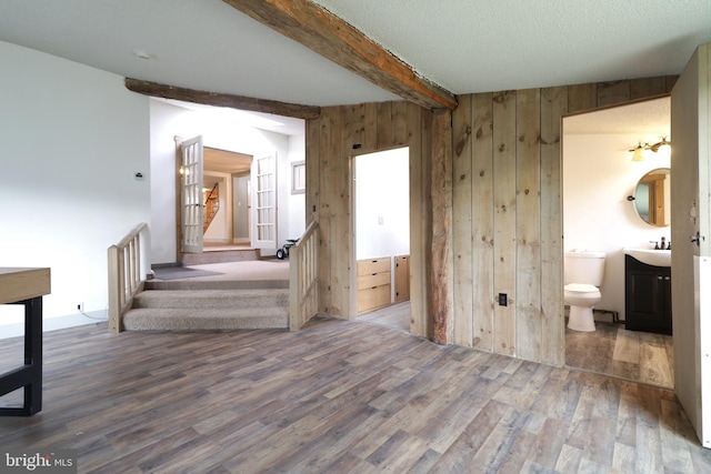 interior space with hardwood / wood-style floors, wood walls, beamed ceiling, and a textured ceiling