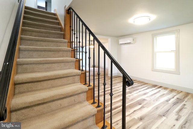 stairway featuring a wall unit AC and wood-type flooring