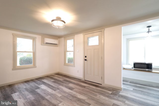 foyer with hardwood / wood-style floors and a wall unit AC