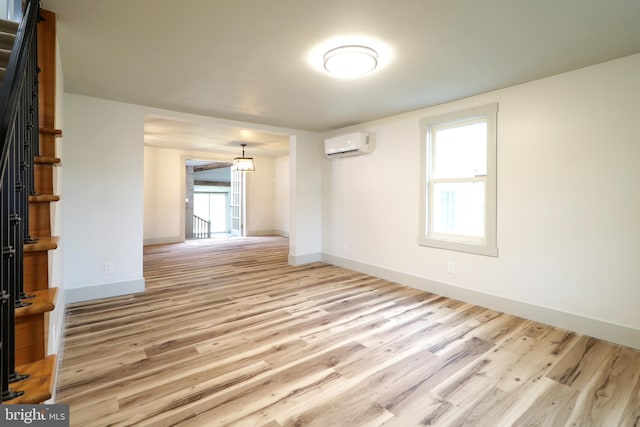 empty room featuring a wall mounted air conditioner and light hardwood / wood-style floors