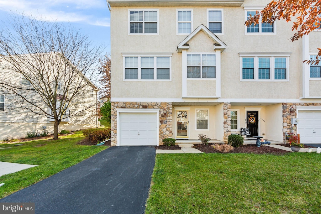 townhome / multi-family property featuring a garage and a front lawn