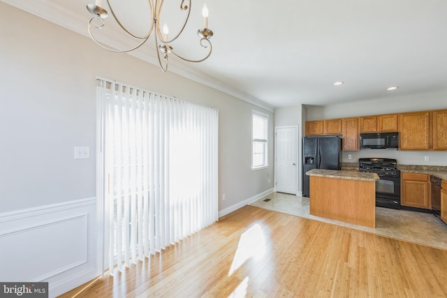 kitchen featuring light wood-type flooring, a kitchen island, crown molding, and black appliances