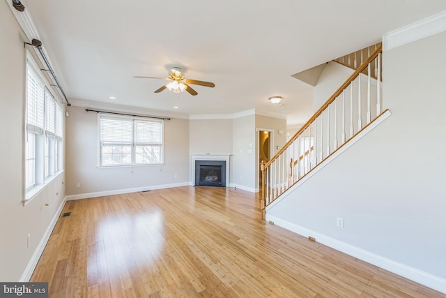 unfurnished living room with light hardwood / wood-style floors, ceiling fan, and crown molding