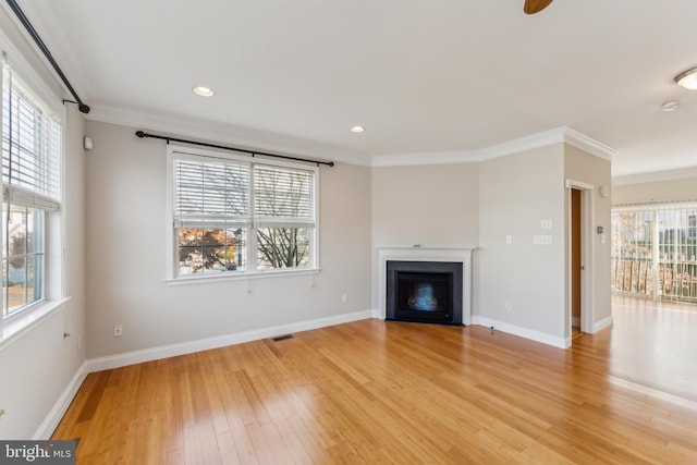 unfurnished living room with a healthy amount of sunlight, light wood-type flooring, and crown molding