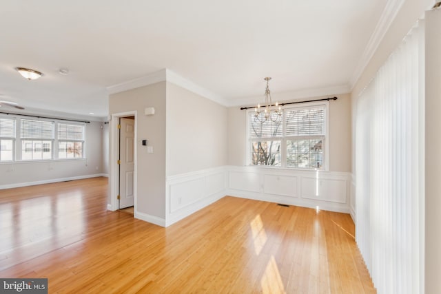 empty room featuring ornamental molding, wood-type flooring, and an inviting chandelier