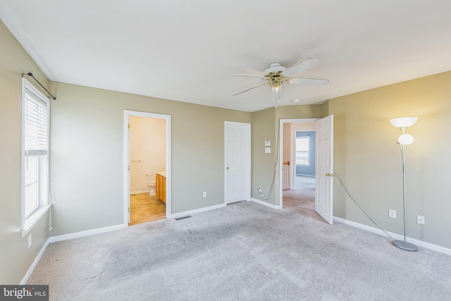 unfurnished bedroom with light carpet, ensuite bath, and ceiling fan