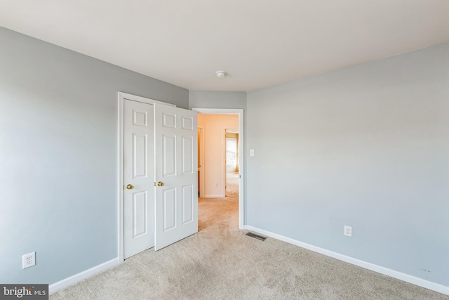 unfurnished bedroom with a closet and light colored carpet