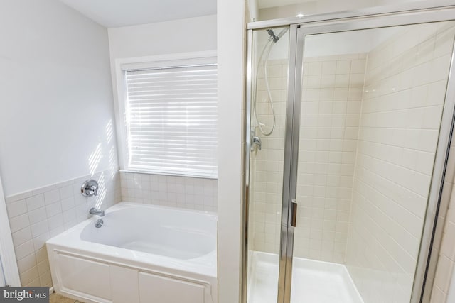 bathroom featuring tile walls and independent shower and bath