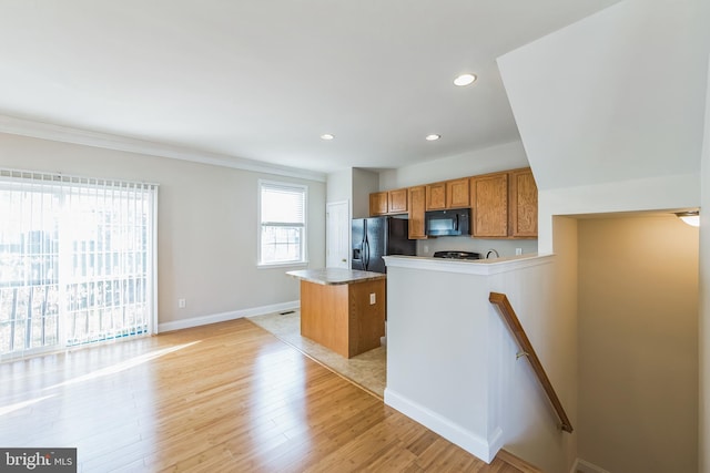 kitchen featuring a center island, light hardwood / wood-style floors, ornamental molding, and black appliances